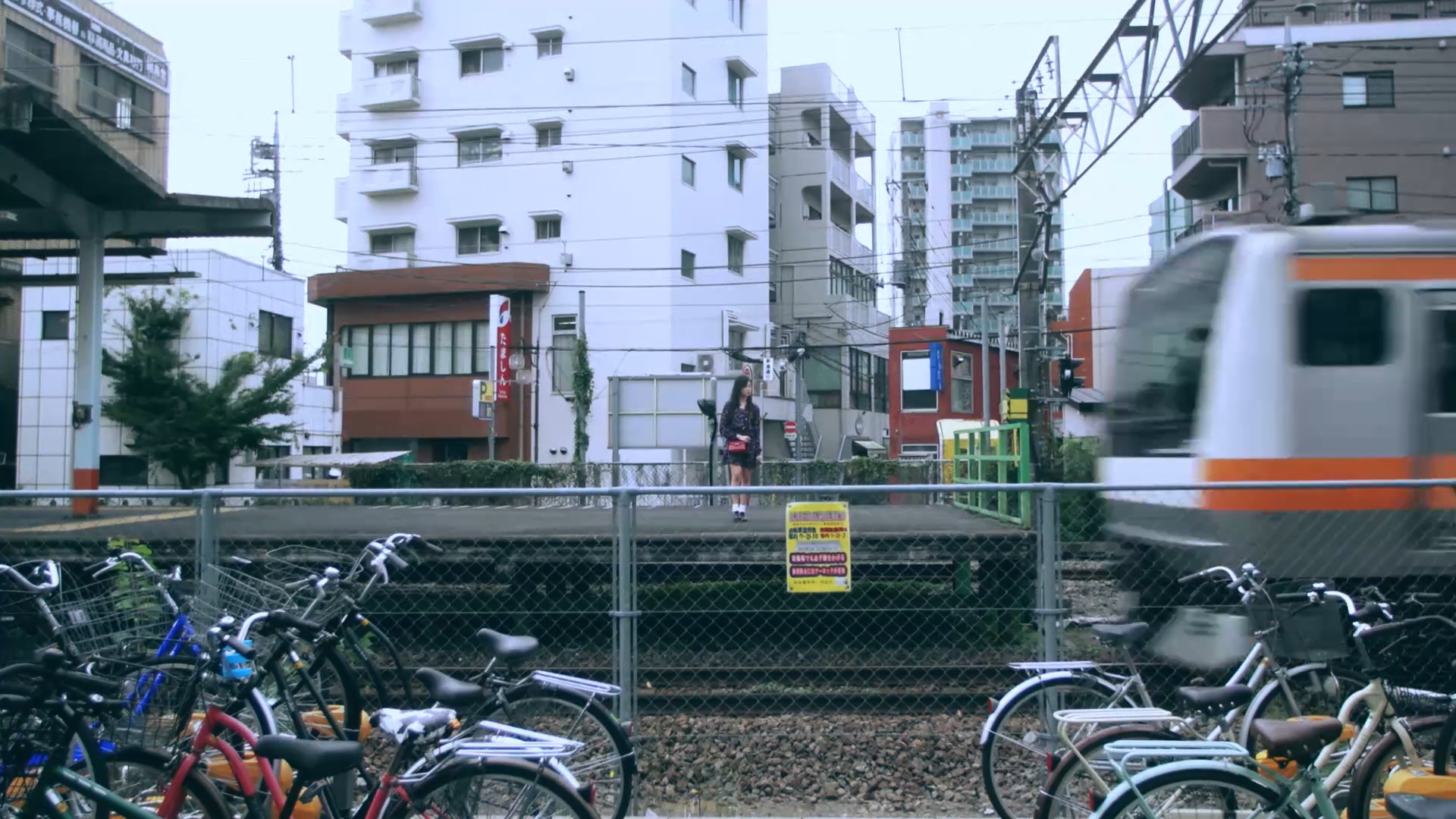 Hyunjin waiting for a train to pass by in front of her, from the 'Around You' music video.